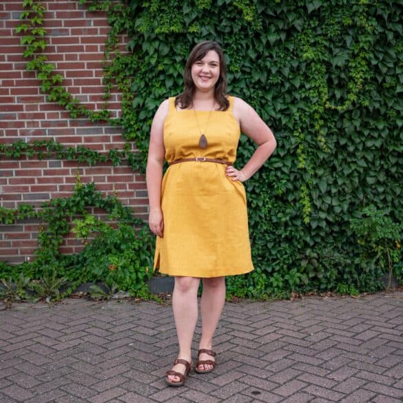 Bri, a white femme casually models a mustard tank dress. 